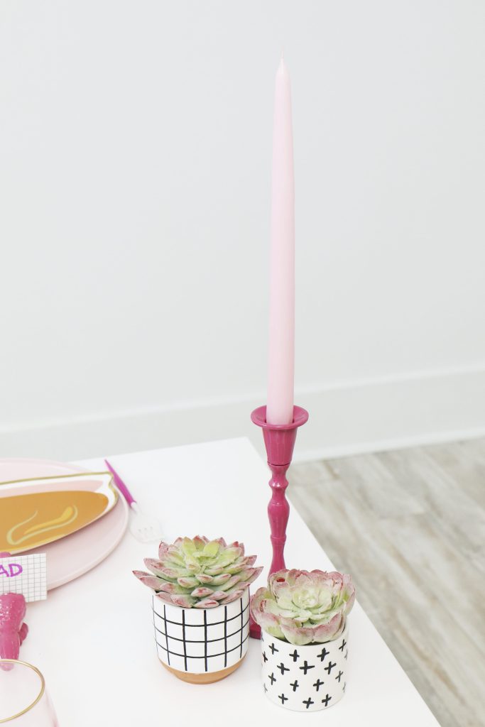 pink taper candle and modern black and white succulent table decor