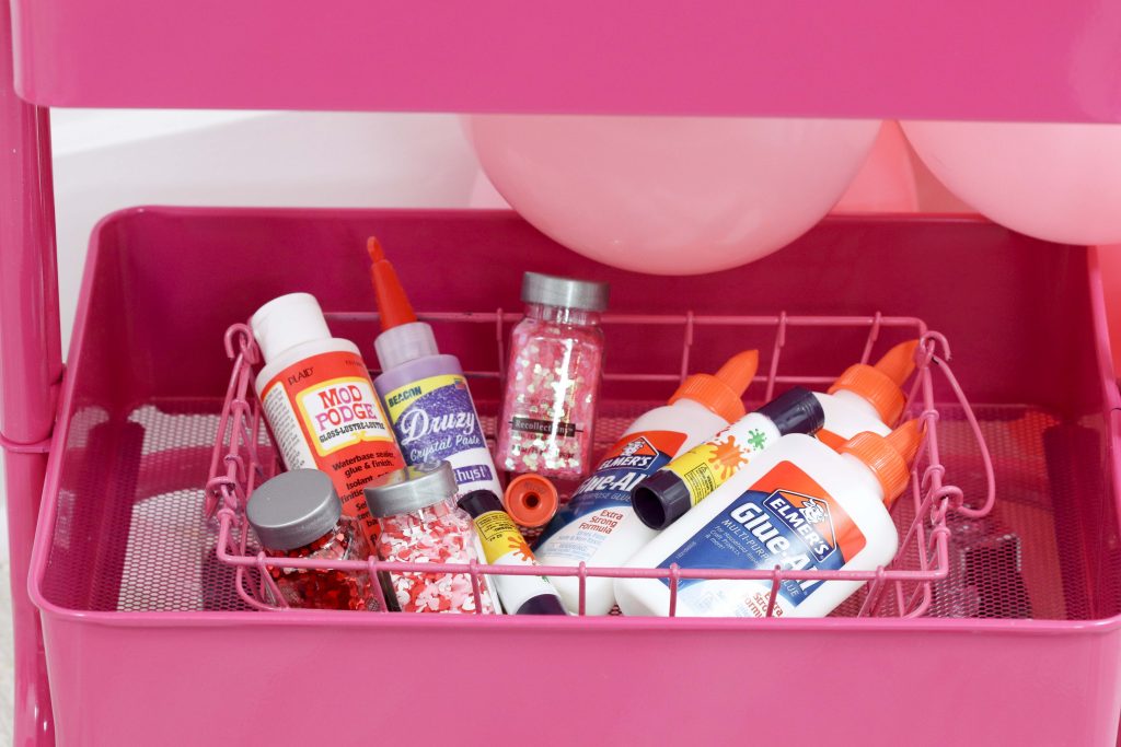 Valentine's craft supply cart for a Valentine's Day Craft Party for Kids with fringe heart backdrop, craft cart, and craft table ideas! Get all of the details now at fernandmaple.com!