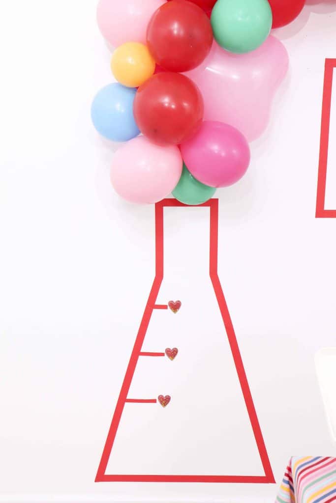 DIY Masking Tape Backdrop - Set up a heart-filled Slime Lab for a fun and entertaining Valentine's Day Slime Party for Kids! Plus, how to create to-go Slime Kits for friends! Get details now at fernandmaple.com!