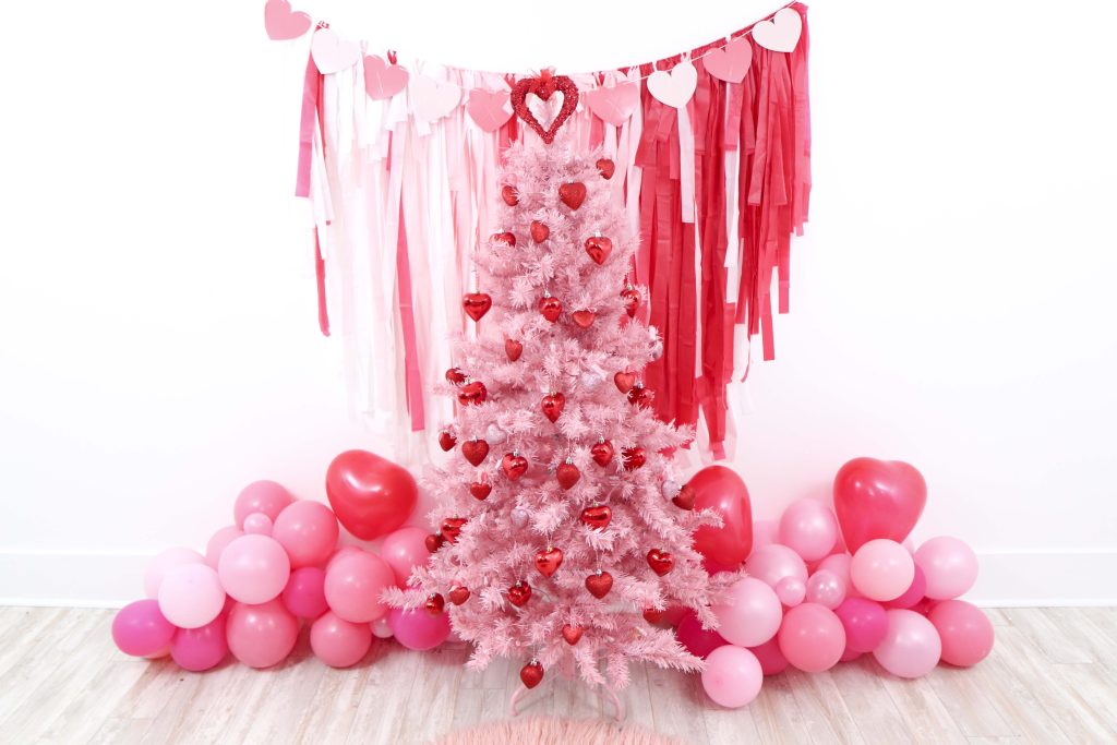 Valentine's Day pink tree- decorate a Valentine's Day tree at a tree decorating party with fun backdrop, decor, and candy heart ornament craft! Get details now at fernandmaple.com.