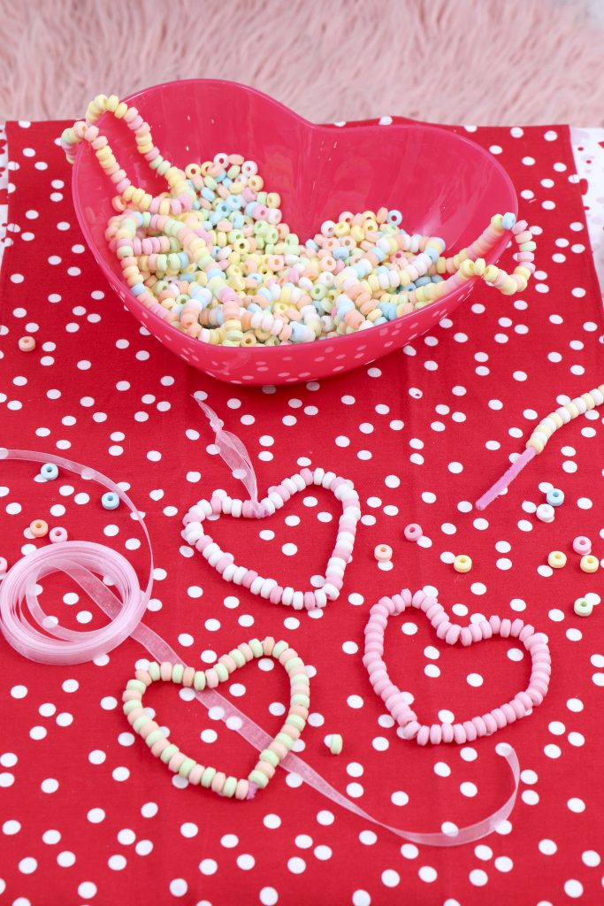 Valentine's Day Candy Heart Ornament station- decorate a Valentine's Day tree at a tree decorating party with fun backdrop, decor, and candy heart ornament craft! Get details now at fernandmaple.com.