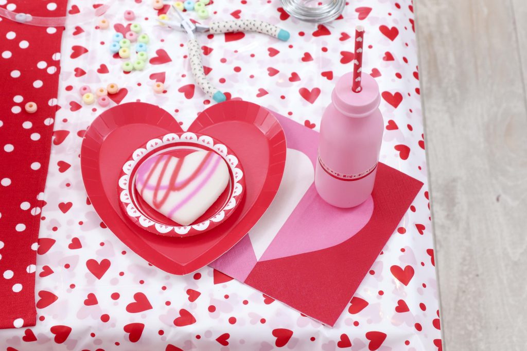 Valentine's Day kid's party place setting - decorate a Valentine's Day tree at a tree decorating party with fun backdrop, decor, and candy heart ornament craft! Get details now at fernandmaple.com.