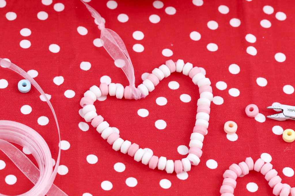 Create cute and edible Valentine's Day Candy Heart Ornaments with kids to hang on a tree or around the house, give as gifts, or treat yourself! Get instructions now at fernandmaple.com!