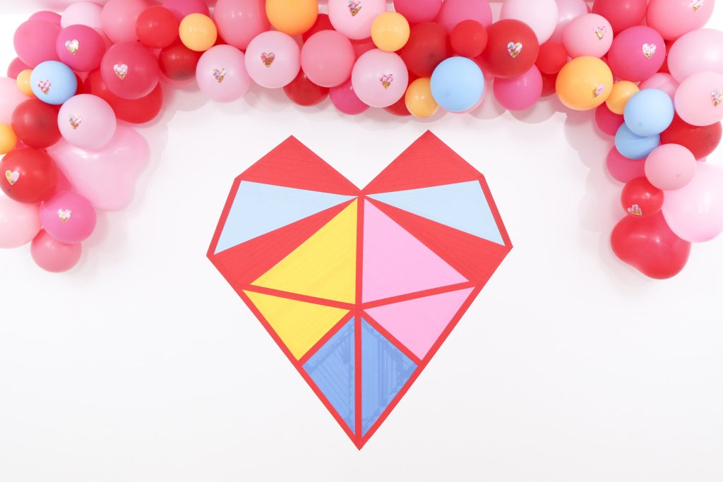 Colorful and modern Geometric Heart Valentine's Day Party DIY backdrop - Get details and more party ideas now at fernandmaple.com!
