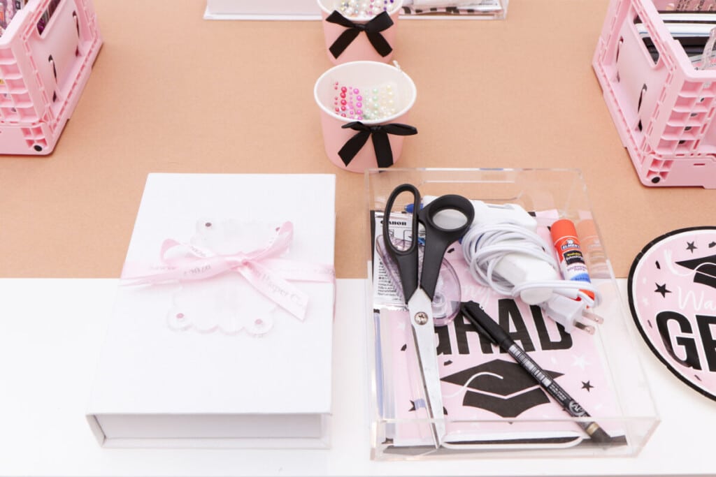 individual graduation party craft station place setting with memory book boxes and an acrylic tray, supplies and pink grad napkin