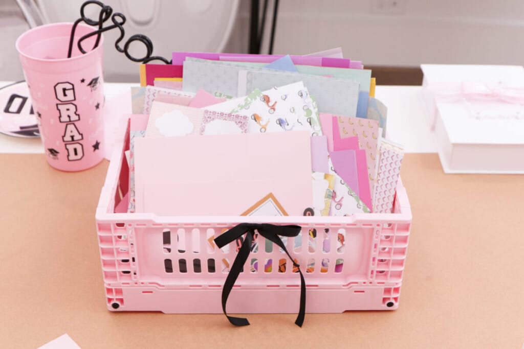 pink crates filled with stickers, stamps and card stock for graduation party craft station