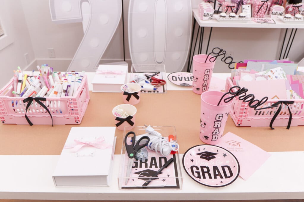 graduation party craft station with book-themed memory boxes, pink crates of supplies and individual acrylic trays