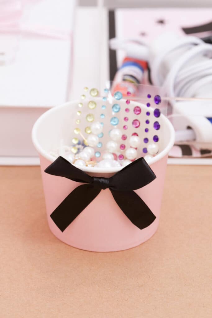 pink containers filled with gem stcikers and flatbacked charms for graduation party craft station
