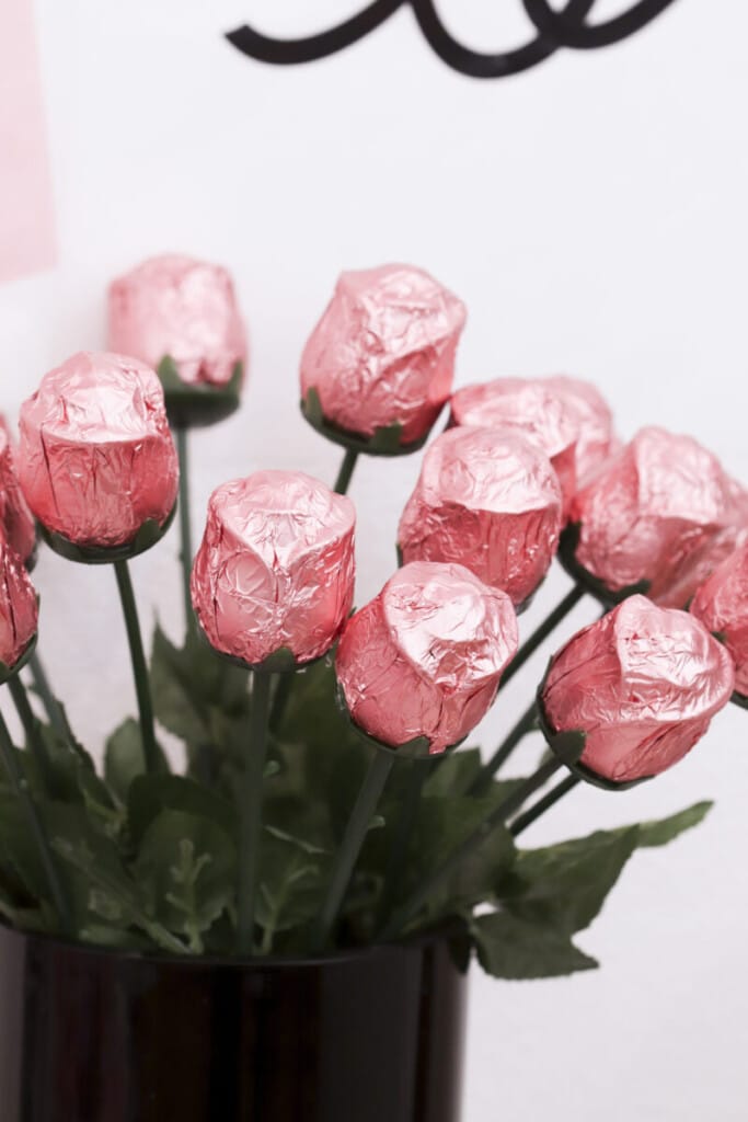 pink chocolate roses in black vase with black bow at graduation party candy bar