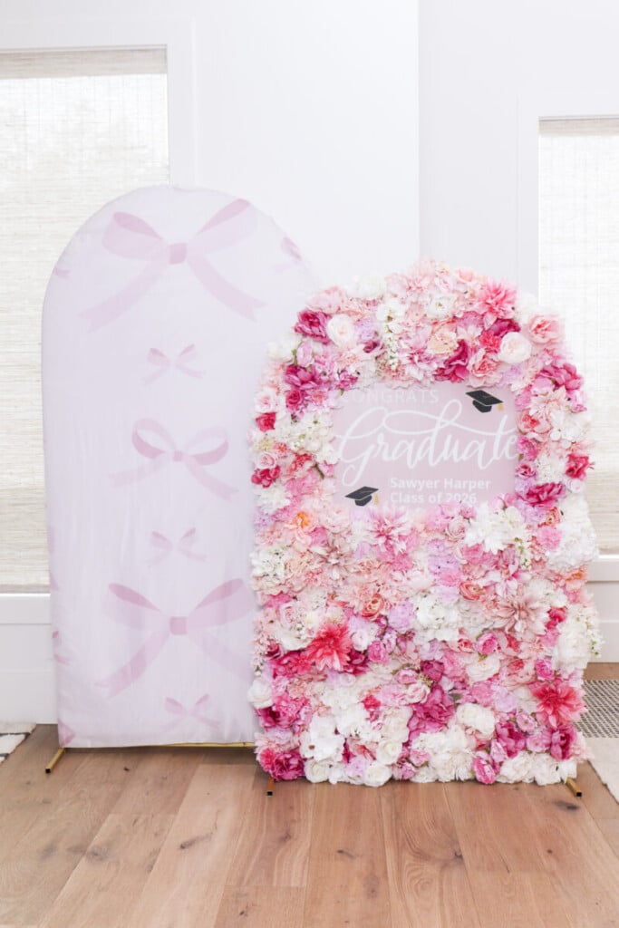 DIY pink floral arch backdrop paired with pink bow fabric arch at graduation party celebration area