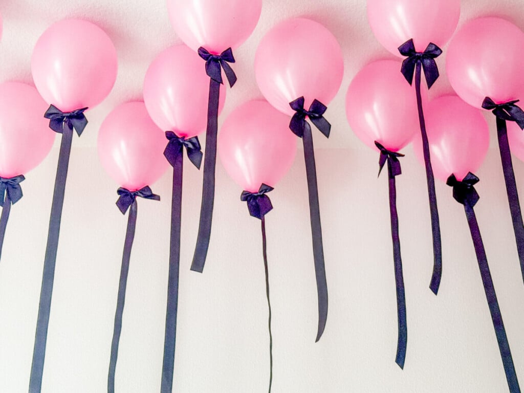 pink ceiling balloons with black ribbon tails and bows at graduation party