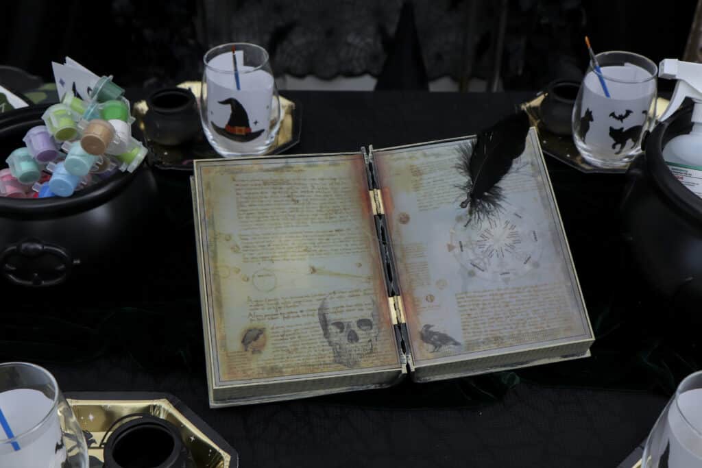 Painting table with a spell book centerpiece for a gothic paint and sip party