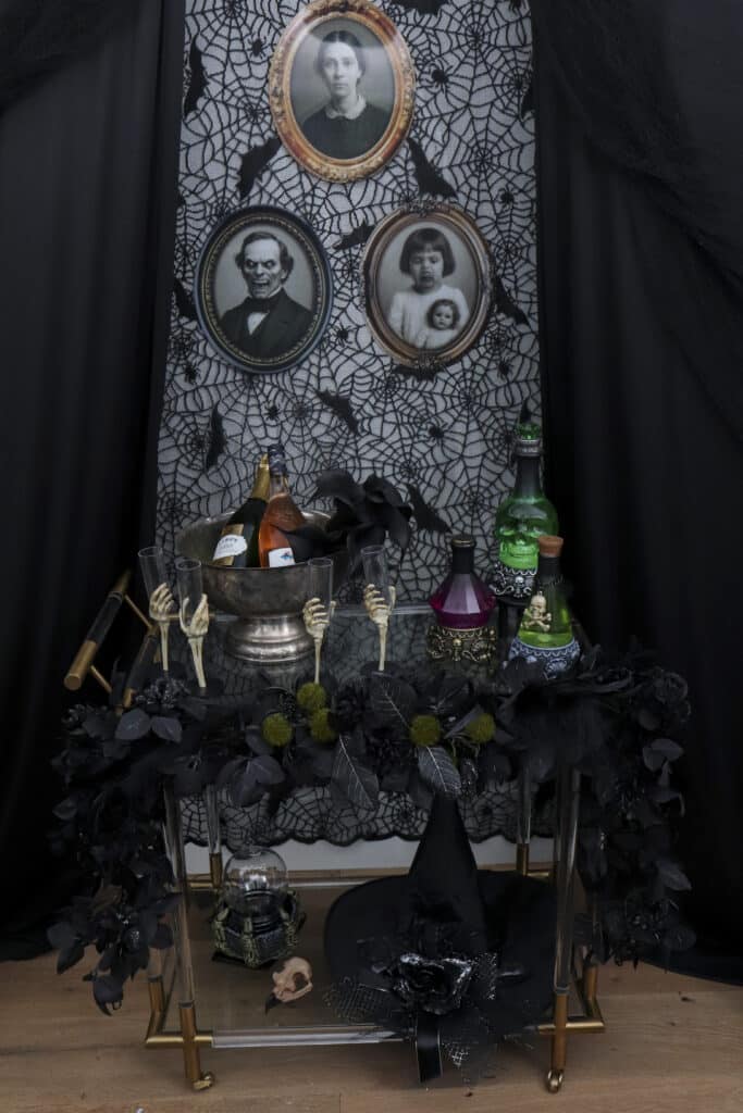 Gothic paint and sip party bar cart in front of lace walls with black draping as curtains
