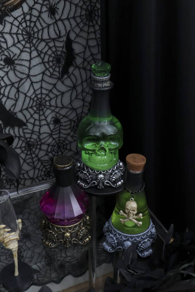 Potion bar cart setup for a gothic Halloween paint and sip party. Potion bottle accents that light up