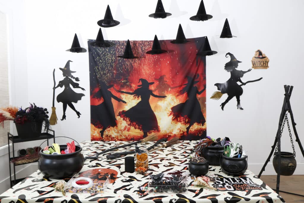 Broom making station set up for a Halloween witch party with dancing witches fire backdrop