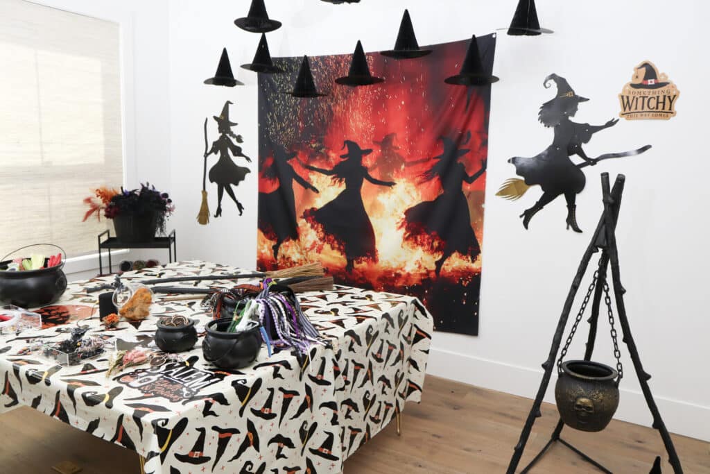 Practical Magic party ideas — broom making station with witch dancing witches backdrop