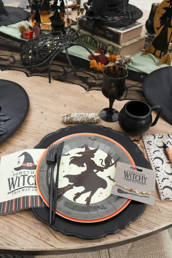 : close-up of witch party place setting with witch plate, Something Witchy napkin and bracelet gift