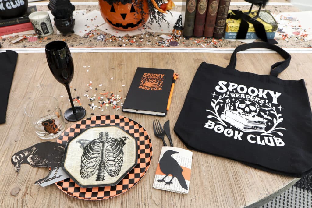 Spooky book club dining table setting with jack-o'-lantern centerpiece and tote book bags